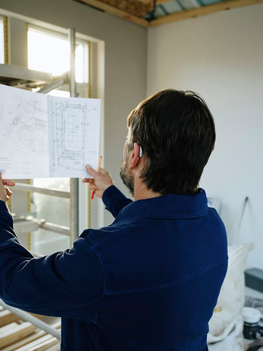 A site worker holding up a floor plan against a window on site